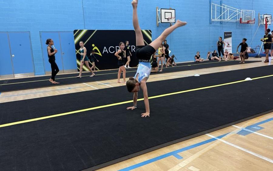 A student training on a tumbling track in a school sports hall